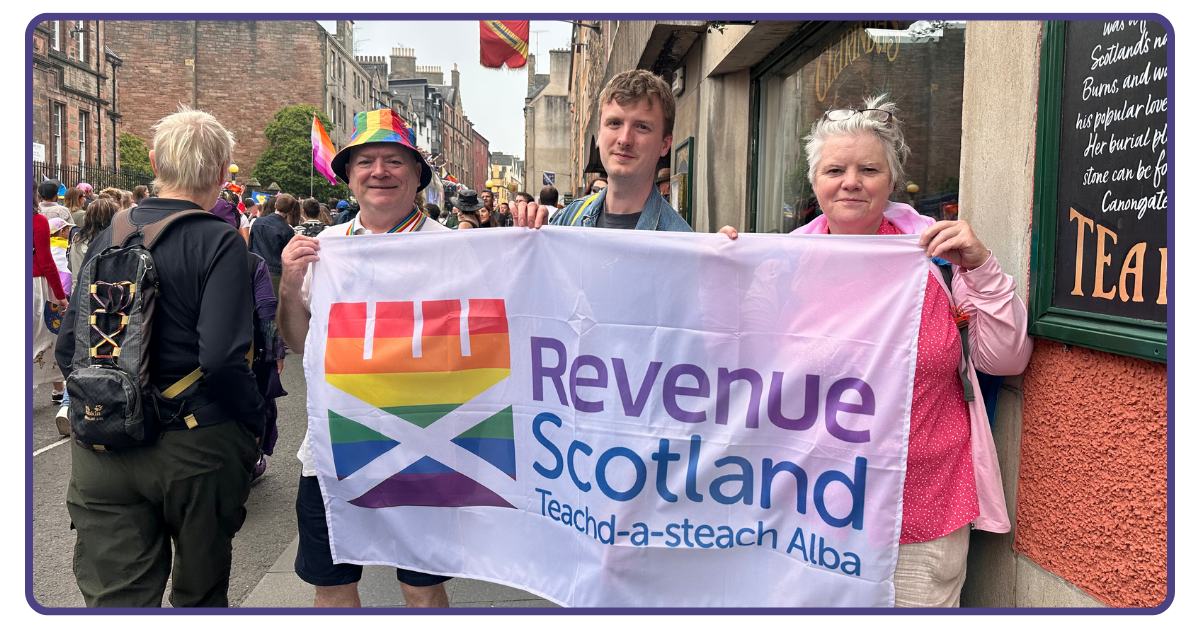 Three members of Revenue Scotland staff holding a flag showing the Pride version of the Revenue Scotland logo